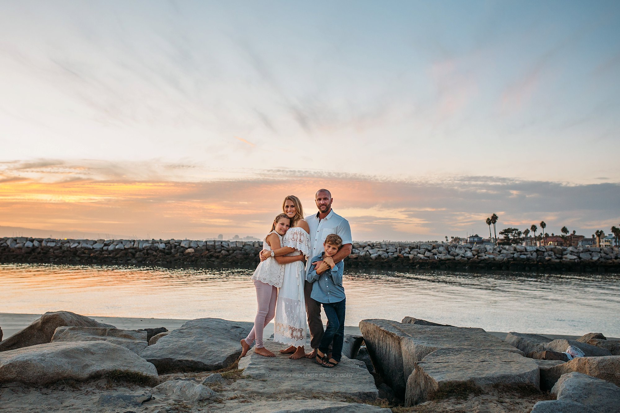 Francesca Marchese Photography family standing on the rocky bluffs at sunset on the beach in Orange County, CA